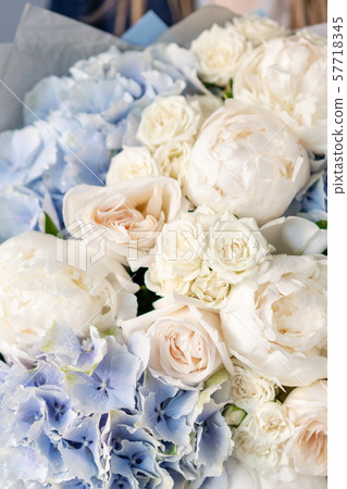 White peonies and blue hydrangea. Beautiful bouquet of mixed flowers in woman hand. Floral shop White peonies and blue hydrangea. Beautiful bouquet of mixed flowers in woman hand. Floral shop 57718345