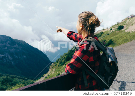 view from the back a woman points a finger in the mountains view from the back a woman points a finger in the mountains 57718349
