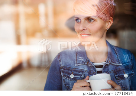 A close-up portrait of young attractive woman standing by window at home. 57718454