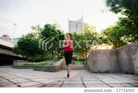 Young woman runner jogging outdoors in city early in the morning. 57718565