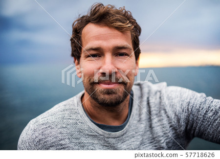 A portrait of handsome man standing outdoors, looking at camera. 57718626