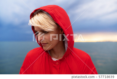 Young woman standing outdoors on beach at dusk. 57718639