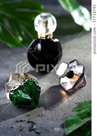Women's perfume in beautiful bottle with green leaves on a black concrete background with bright Women's perfume in beautiful bottle with green leaves on a black concrete background with bright 57718745