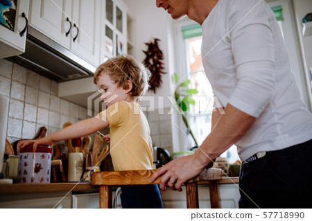 Unrecognizable father with a toddler son in a kitchen at home. Unrecognizable father with a toddler son in a kitchen at home. 57718990