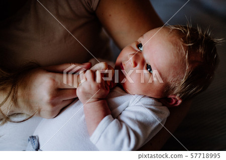 A midsection of mother with a newborn baby at home. A midsection of mother with a newborn baby at home. 57718995