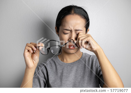 Women hold glasses and suffer from eye pain. Women hold glasses and suffer from eye pain. 57719077