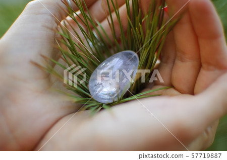 Female hand with transparent amethyst quartz yoni egg for vumfit, imbuilding or meditation. Shining 57719887