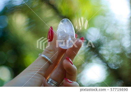 Female hand with transparent amethyst quartz yoni egg for vumfit, imbuilding or meditation. Shining Female hand with transparent amethyst quartz yoni egg for vumfit, imbuilding or meditation. Shining 57719890