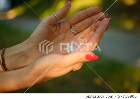 Female hand with transparent amethyst quartz yoni egg for vumfit, imbuilding or meditation. Shining 57719906