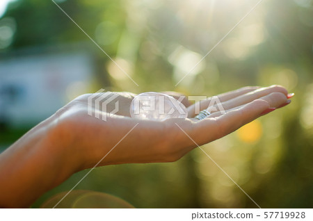 Female hand with transparent amethyst quartz yoni egg for vumfit, imbuilding or meditation. Shining 57719928