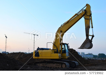 Excavator at a construction site on a background sunset. Excavator at a construction site on a background sunset. 57719982