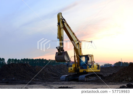 Excavator at a construction site on a background sunset.  57719983