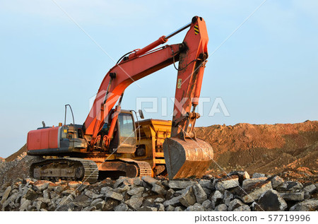 Heavy tracked excavator load stone, old asphalt or concrete waste into a mobile jaw crusher machine. 57719996