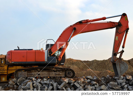 Heavy tracked excavator load stone, old asphalt or concrete waste into a mobile jaw crusher machine. 57719997