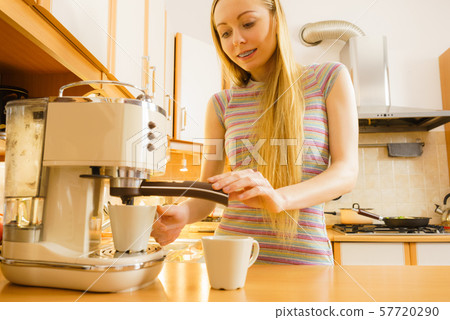 Woman in kitchen making coffee from machine Woman in kitchen making coffee from machine 57720290