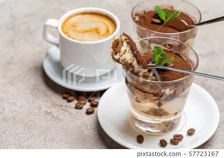Portion of Classic tiramisu dessert in a glass and cup of coffee on concrete background 57723167