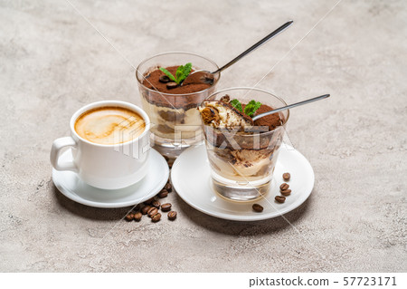 Portion of Classic tiramisu dessert in a glass and cup of coffee on concrete background 57723171