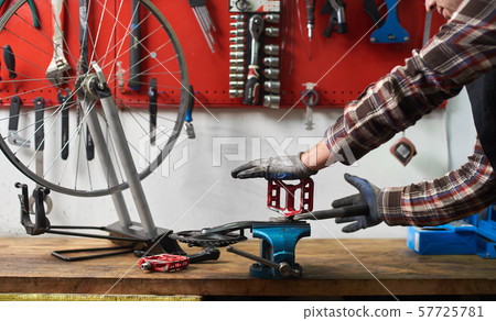 Male mechanic working in bicycle repair shop using tools Male mechanic working in bicycle repair shop using tools 57725781