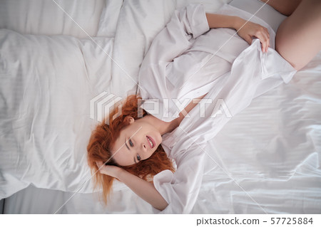 red-haired girl in the men's shirt is lying on the 57725884
