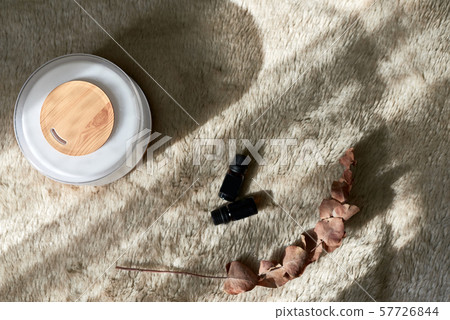 Aromatherapy diffucer device with bottles of oils. Top view with sunlight shadows. Cozy 57726844