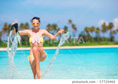 Beautiful girl with equipment on large stones ready for snorkeling Beautiful girl with equipment on large stones ready for snorkeling 57729468