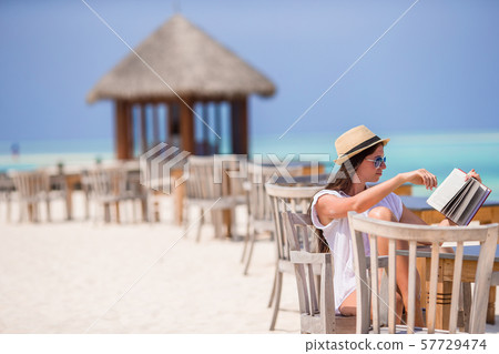 Young woman reading at outdoor beach cafe Young woman reading at outdoor beach cafe 57729474