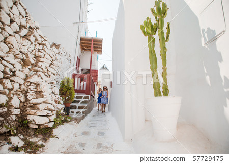 Family vacation in Europe. Father and kids at street of typical greek traditional village on Mykonos Family vacation in Europe. Father and kids at street of typical greek traditional village on Mykonos 57729475