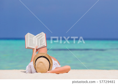 Portrait of a young woman relaxing on the beach, reading a book Portrait of a young woman relaxing on the beach, reading a book 57729481