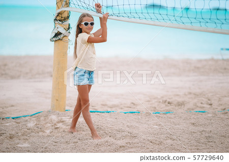 Little adorable girl playing voleyball on beach with ball. Little adorable girl playing voleyball on beach with ball. 57729640