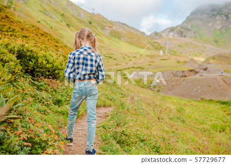 Beautiful happy little girl in mountains in the background of fog Beautiful happy little girl in mountains in the background of fog 57729677