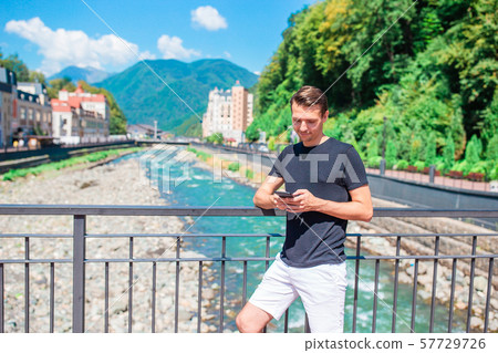 Man on the embankment of a mountain river in a European city. Man on the embankment of a mountain river in a European city. 57729726