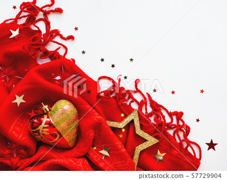 Christmas and New Year background. Bright red scarf with golden stars and confetti on white background. Folded warm accessory with copy space. 57729904