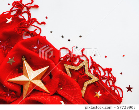 Christmas and New Year background. Bright red scarf with golden stars and confetti on white background. Folded warm accessory with copy space. Christmas and New Year background. Bright red scarf with golden stars and confetti on white background. Folded warm accessory with copy space. 57729905