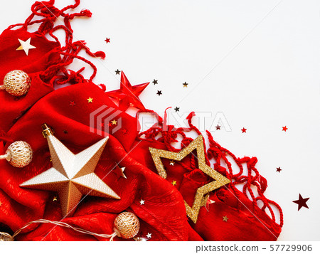 Christmas and New Year background. Bright red scarf with golden stars and confetti on white background. Folded warm accessory with copy space. 57729906