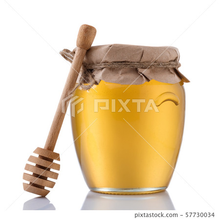Glass jar full of honey and wooden stick on a white background. 57730034
