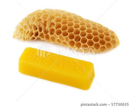 A bar of natural beeswax and a piece of bee honey on a white background. Beekeeping products A bar of natural beeswax and a piece of bee honey on a white background. Beekeeping products 57730035