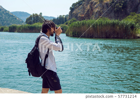 man in a shirt and shorts photographs on camera the river and the mountain man in a shirt and shorts photographs on camera the river and the mountain 57731214