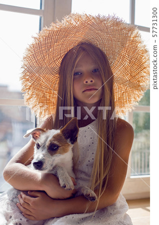 girl in a white dress and a straw hat sitting on the windowsill 57731300