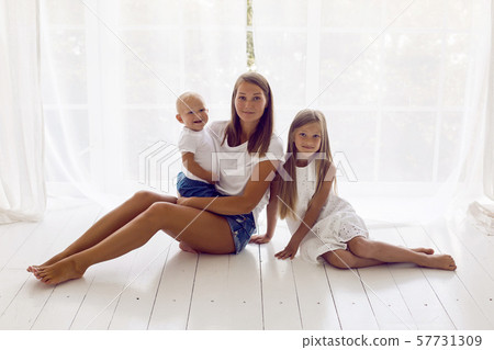 mother with daughter and son sitting on a white wooden floor 57731309