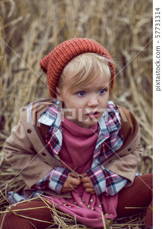 baby girl sitting in a warm orange hat baby girl sitting in a warm orange hat 57731314