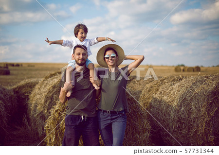 family mom dad son stand in a sloping field near the haystacks family mom dad son stand in a sloping field near the haystacks 57731344