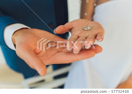 Close-up. Hand of bride and groom. Bride and groom hold hands. Focus on the rings. Bouquet in hand. Close-up. Hand of bride and groom. Bride and groom hold hands. Focus on the rings. Bouquet in hand. 57732430