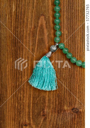 Green jade rosary on a brown wooden table Green jade rosary on a brown wooden table 57732765