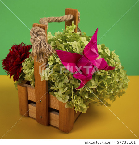 origami butterfly on a green bush in a basket on a colored background beautiful bouquet close shot 57733101