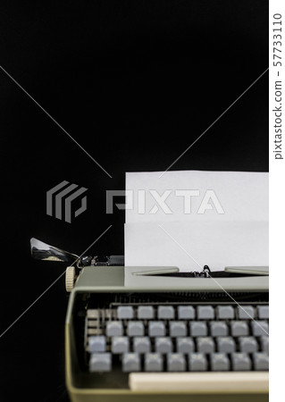 Typewriter on the table on a black background with white paper with empty space. Workplace of the 57733110