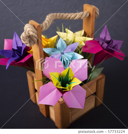Macro Handmade colored paper flowers origami bouquet paper craft art in a basket with grass in the 57733224