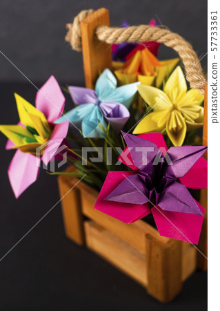 Handmade colored paper flowers origami bouquet paper craft art in a basket with grass in the studio Handmade colored paper flowers origami bouquet paper craft art in a basket with grass in the studio 57733361