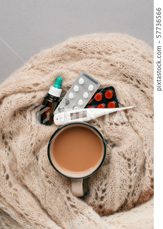 Tea mug covered with warm scarf, thermometer and 57736566