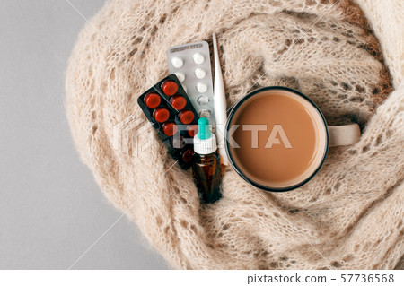 Tea mug covered with warm scarf, thermometer and 57736568