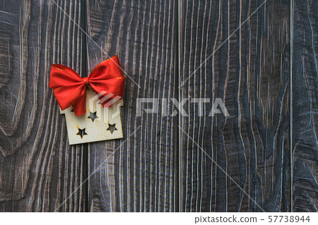 Christmas background with wooden decorative gift and red bow on the old wooden board 57738944